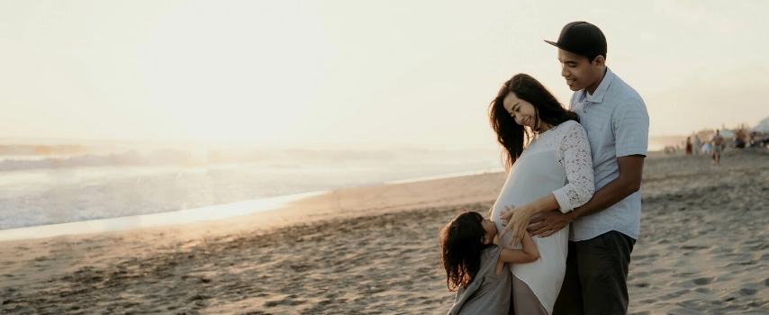 Pregnant mother with family on beach holiday