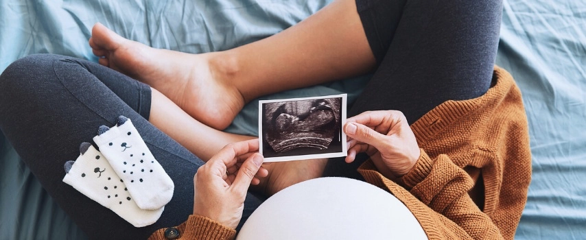 Pregnant woman holding ultrasound image