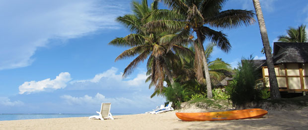 A lone beach chair and palm trees at Palm Grove's Beach, Vaimaaga, Rarotonga, Cook Islands