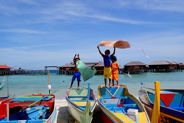 Cover-More New Zealand Facebook photo competition winner: Children playing on colourful boats on a Malaysian beach 